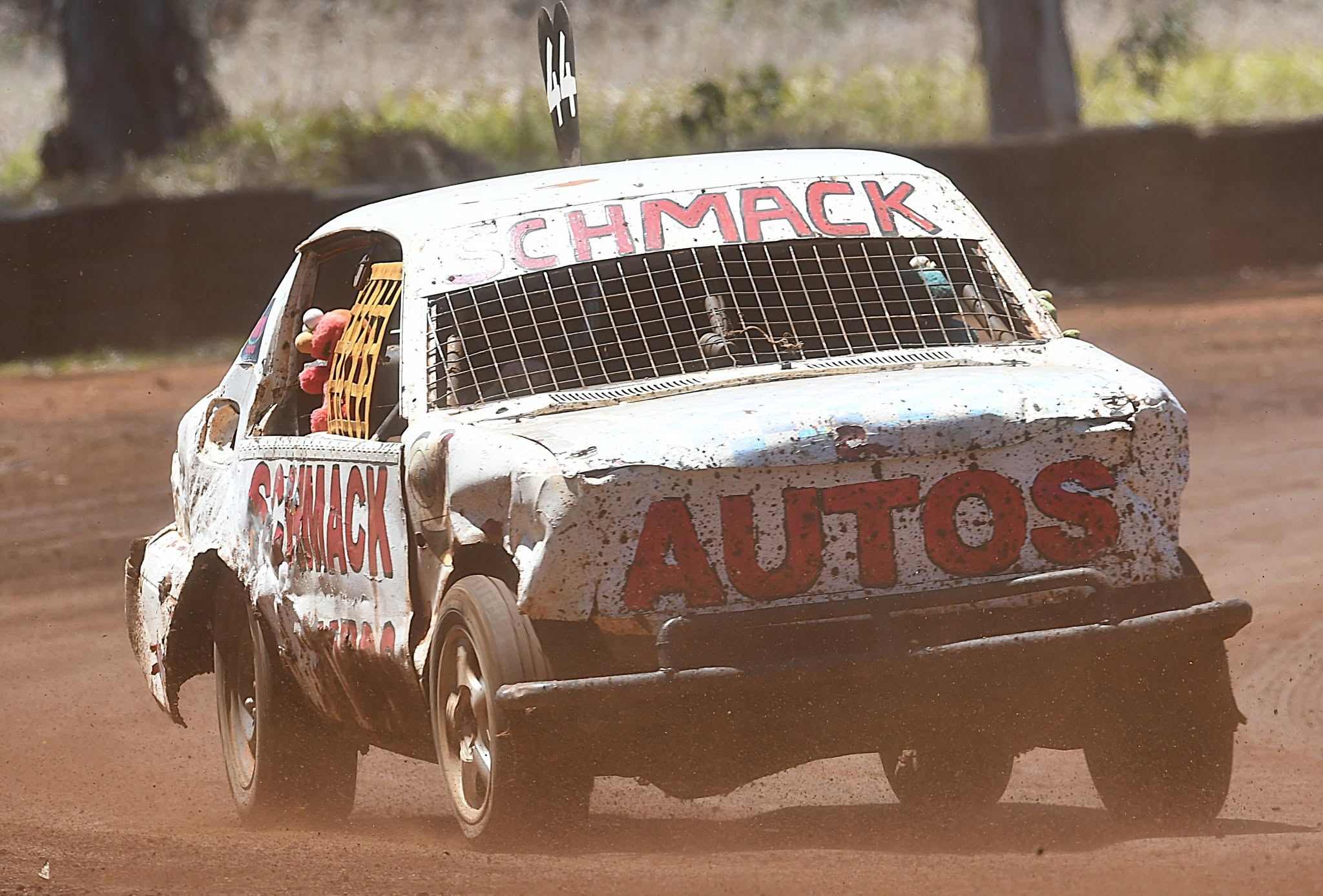 White Schmack Autos race car rounding a corner on a dirt track