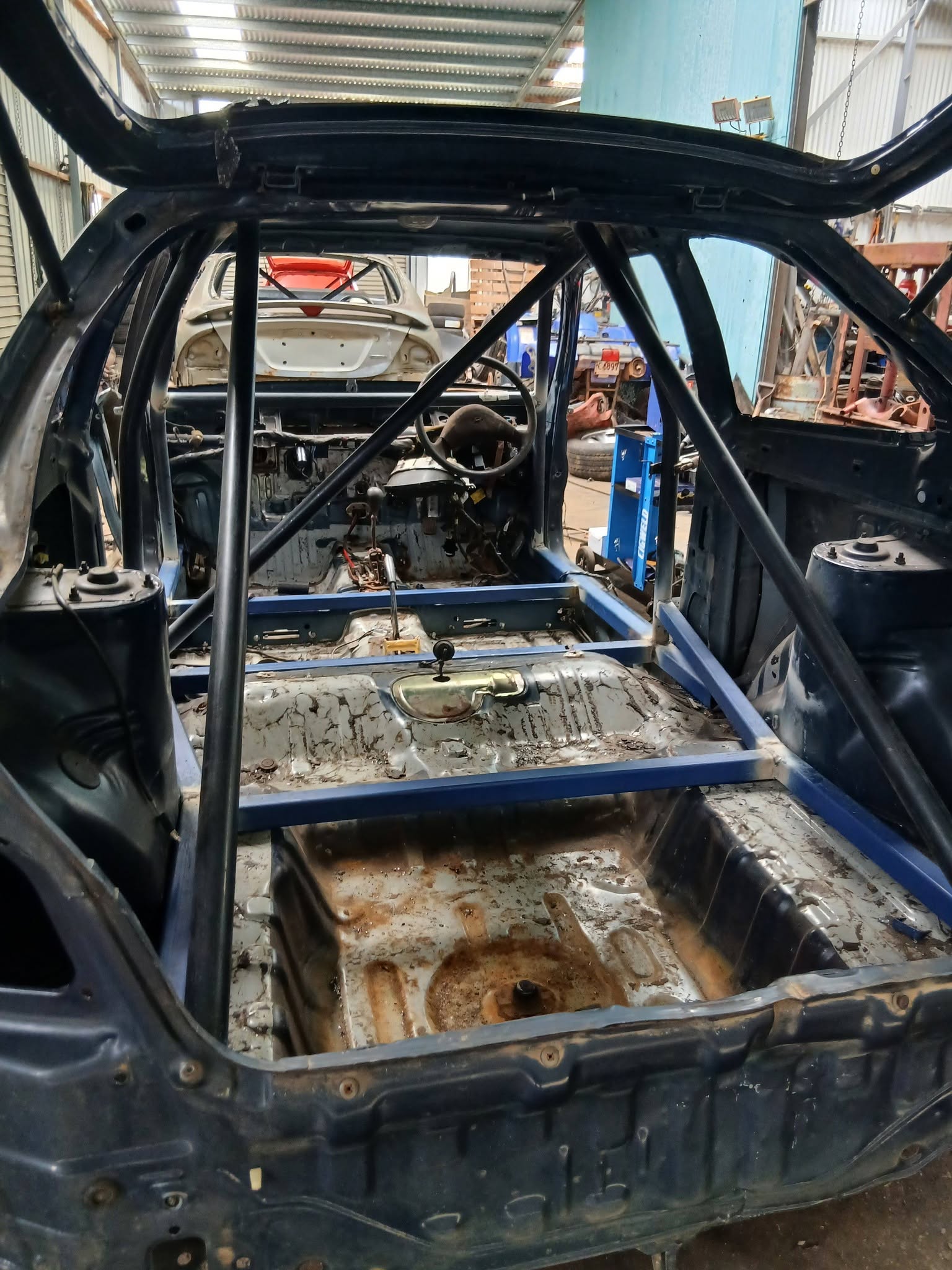 Stripped car shell with a welded roll cage inside the workshop